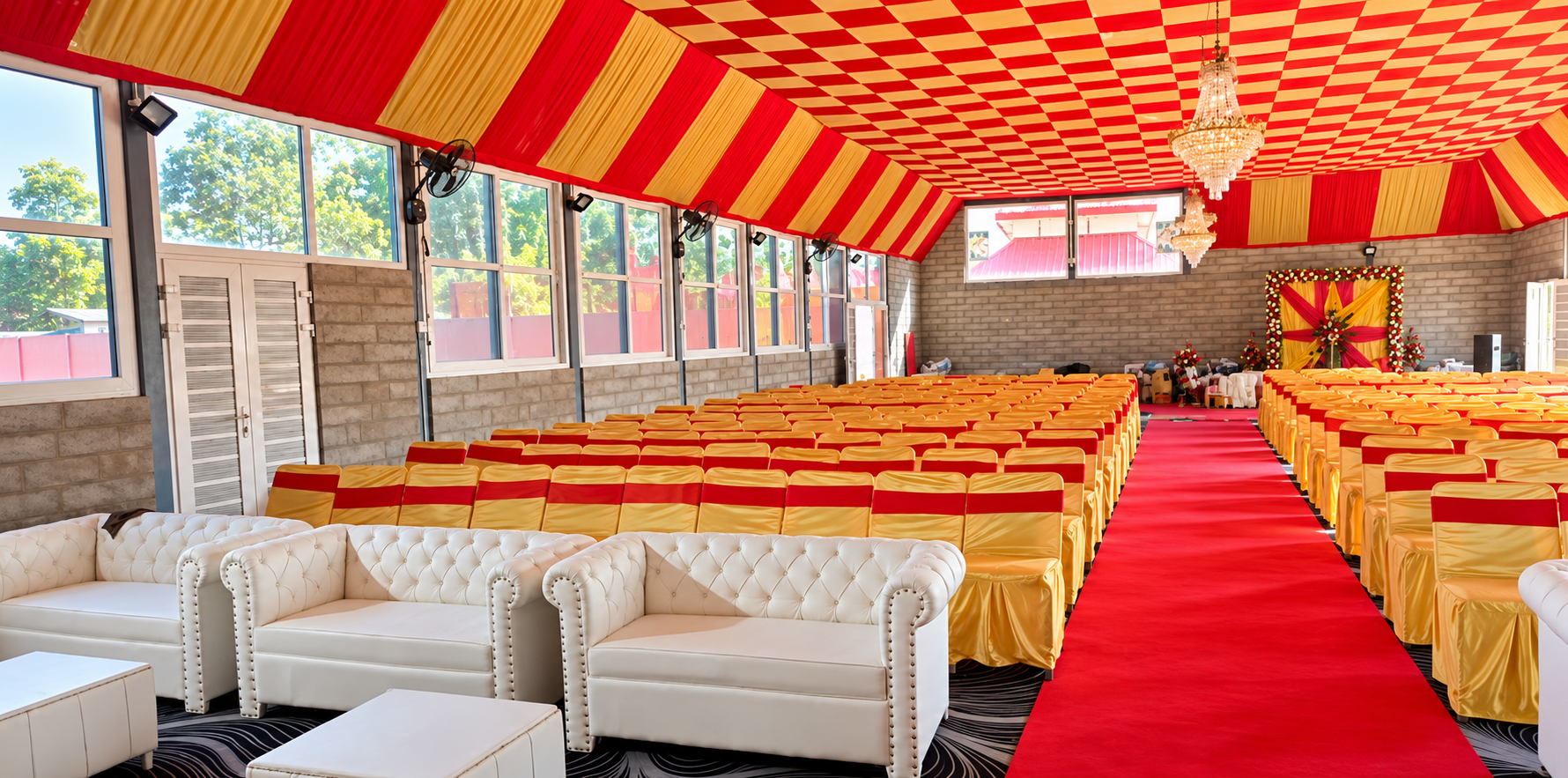 Ved Banquet Hall interior decorated for a wedding with gold and red chairs, a red carpet aisle and a floral stage